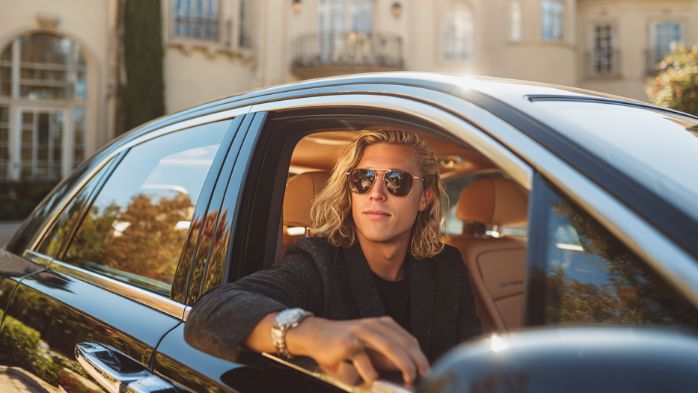 man sitting in a rolls royce outside of a mansion | life architecture