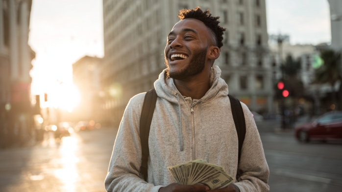 young man walking through city streets with cash | advice to graduates